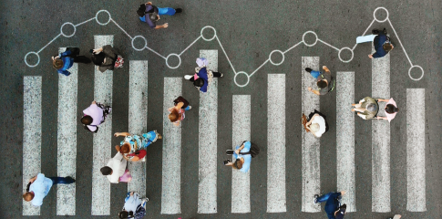 A group of people, representing ALICE individuals, walks on a crosswalk where the lines resemble a bar graph